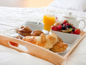 breakfast in bed with fruits and pastries on a tray